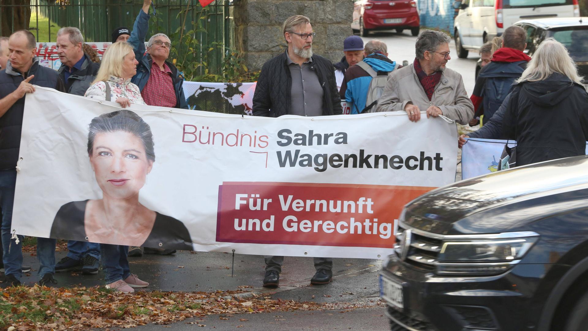 Demonstranten tragen ein Plakat des BSW, darauf ist Sahra Wagenknecht abgebildet.