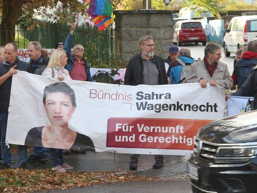 Demonstranten tragen ein Plakat des BSW, darauf ist Sahra Wagenknecht abgebildet.