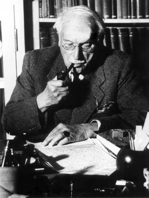 Der Schweizer Psychologe und Psychiater Carl Gustav Jung sitzt vor Unterlagen an seinem Schreibtisch. (undatierte Aufnahme)