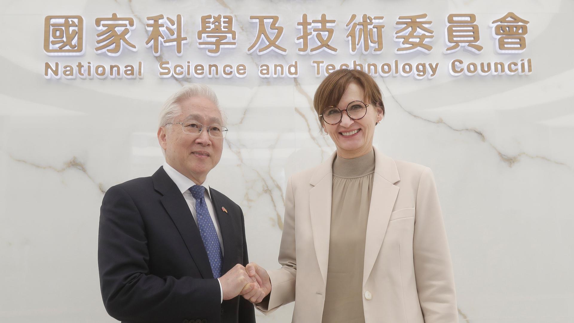Tsung-Tsong Wu, Taiwans Minister für Wissenschaft und Technologie, begrüßt Bettina Stark-Watzinger, Bundesbildungsministerin, im Wissenschaftsministerium in Taipeh. Beide schauen lächelnd in die Kamera und geben sich die Hand.