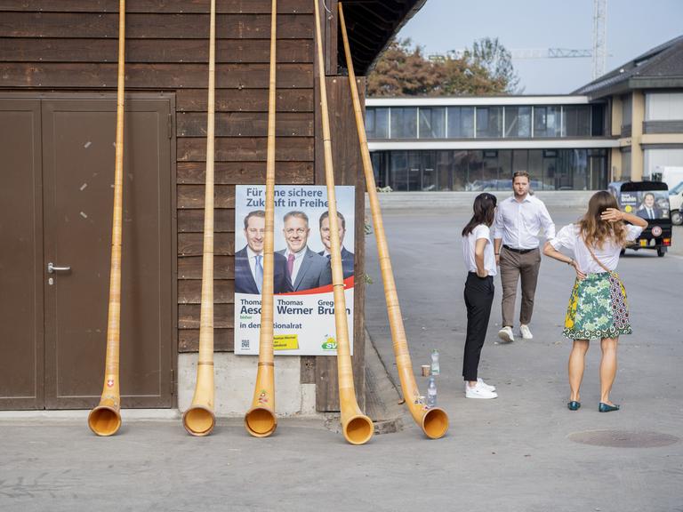 Mehrere Alphörner verdecken ein SVP Wahlplakat, das anläslich eines Parteitages der SVP in Zug an einem Holzhaus hängt.