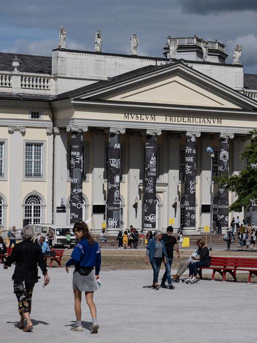 Besucher der documenta fifteen stehen vor dem Museum Fridericianum in Kassel. 