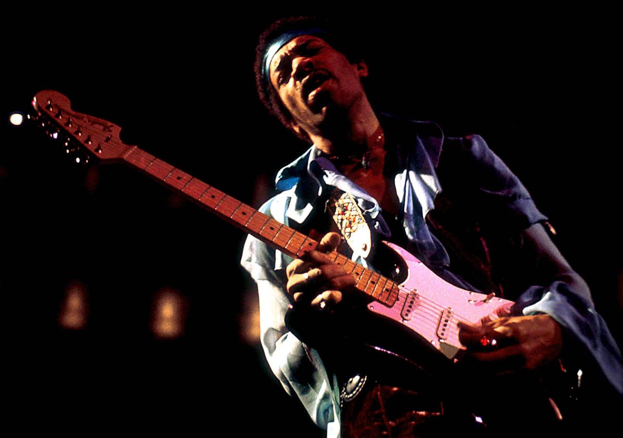 Jimi Hendrix steht mit seiner E-Gitarre auf einer Bühne