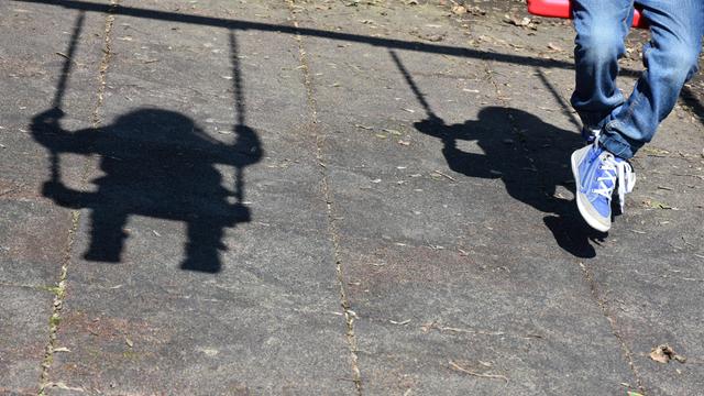 Schatten eines schaukelnden Kindes auf Asphaltboden. Ein Symbolbild für Kinder ohne Geburtsurkunde.