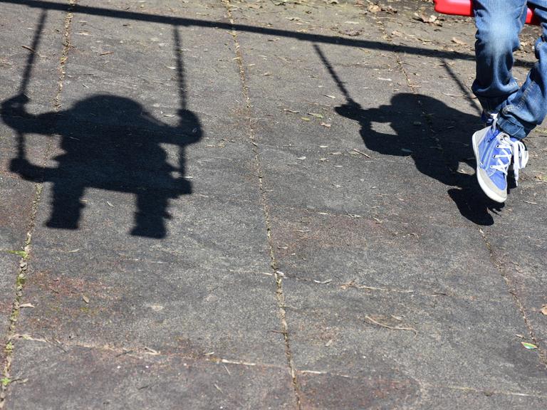 Schatten eines schaukelnden Kindes auf Asphaltboden. Ein Symbolbild für Kinder ohne Geburtsurkunde.