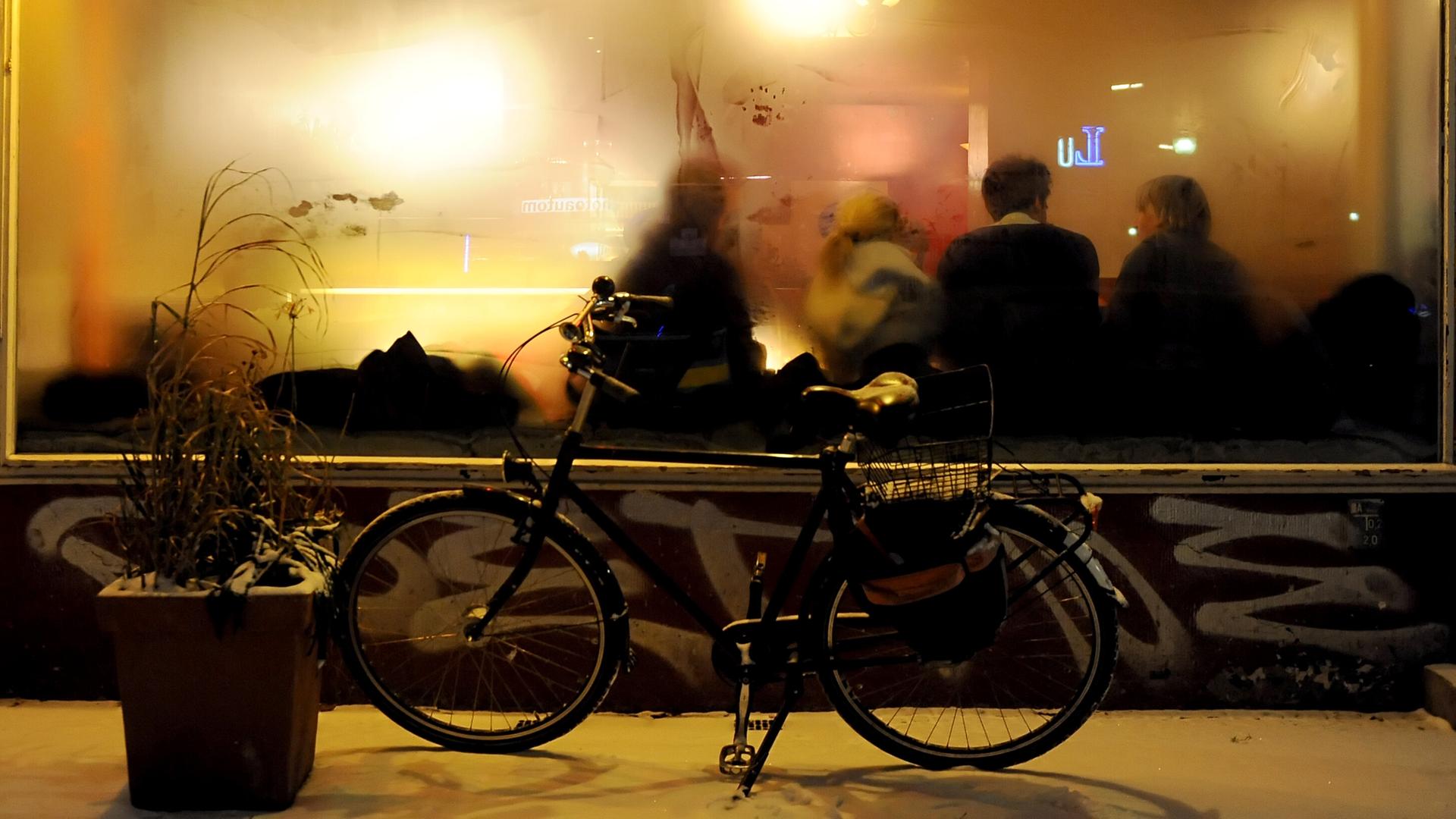 Ein Fahrrad steht vor einer Kneipe mit beschlagenen Fenstern. 