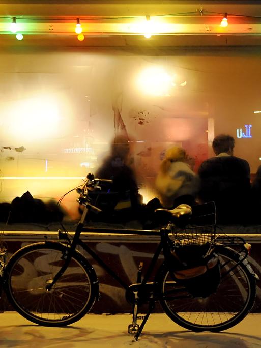 Ein Fahrrad steht vor einer Kneipe mit beschlagenen Fenstern. 