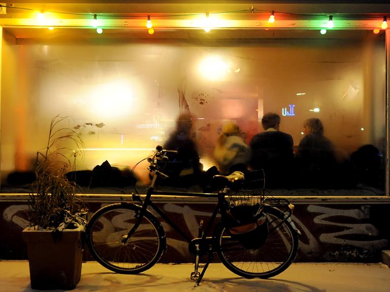 Ein Fahrrad steht vor einer Kneipe mit beschlagenen Fenstern. 