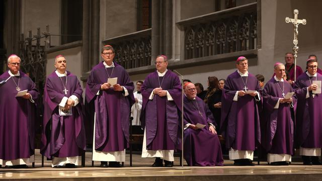 Die Bischöfe sind bei einem Gottes-Dienst in einer Kirche in Augsburg. Sie haben violette Gewänder und Kappen an.