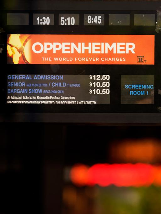 Auf einer Anzeigentafel sind die beiden Filme "Oppenheimer" und "Barbie" annonciert.