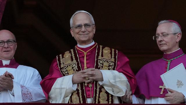 Der neu gewählte Papst, Leo XIV, steht auf dem Balkon des Petersdoms im Vatikan am 8. Mai 2025. Seine Hände sind gefaltet und er hat ein Lächeln auf den Lippen - Er scheint sichtlich glücklich über sein neues Amt.