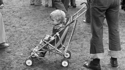 Ein Kind sitzt in einem Kinderwagen.