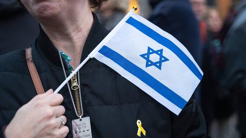 Eine Teilnehmerin trägt als symbolisches Zeichen der Solidarität eine Halskette mit dem Schriftzug "Bring Them Home Now", eine gelbe Schleife und eine kleine Israel-Fahne während einer pro-israelischen Kundgebung in Berlin
