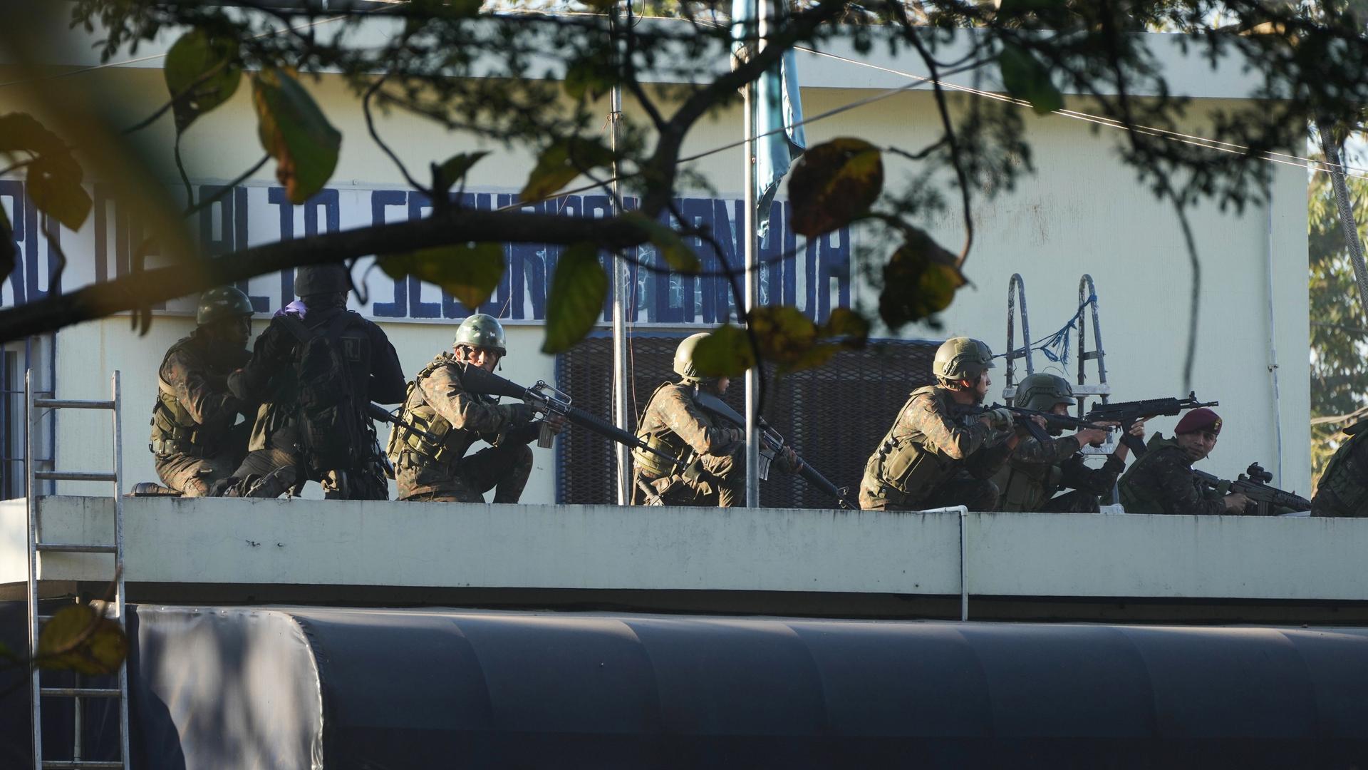 Schwer bewaffnete Sicherheitskräfte bringen sich auf einem Dachvorsprung in Stellung. (AP Photo/Moises Castillo)