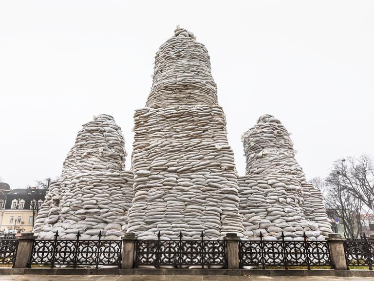 Mit Sandsäcken versucht man ein ukrainisches Denkmal vor einem möglichen Bombardement durch Russland zu schützen.