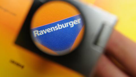 Das blaue Dreiecks-Logo von Ravensburger durch eine Lupe fotografiert