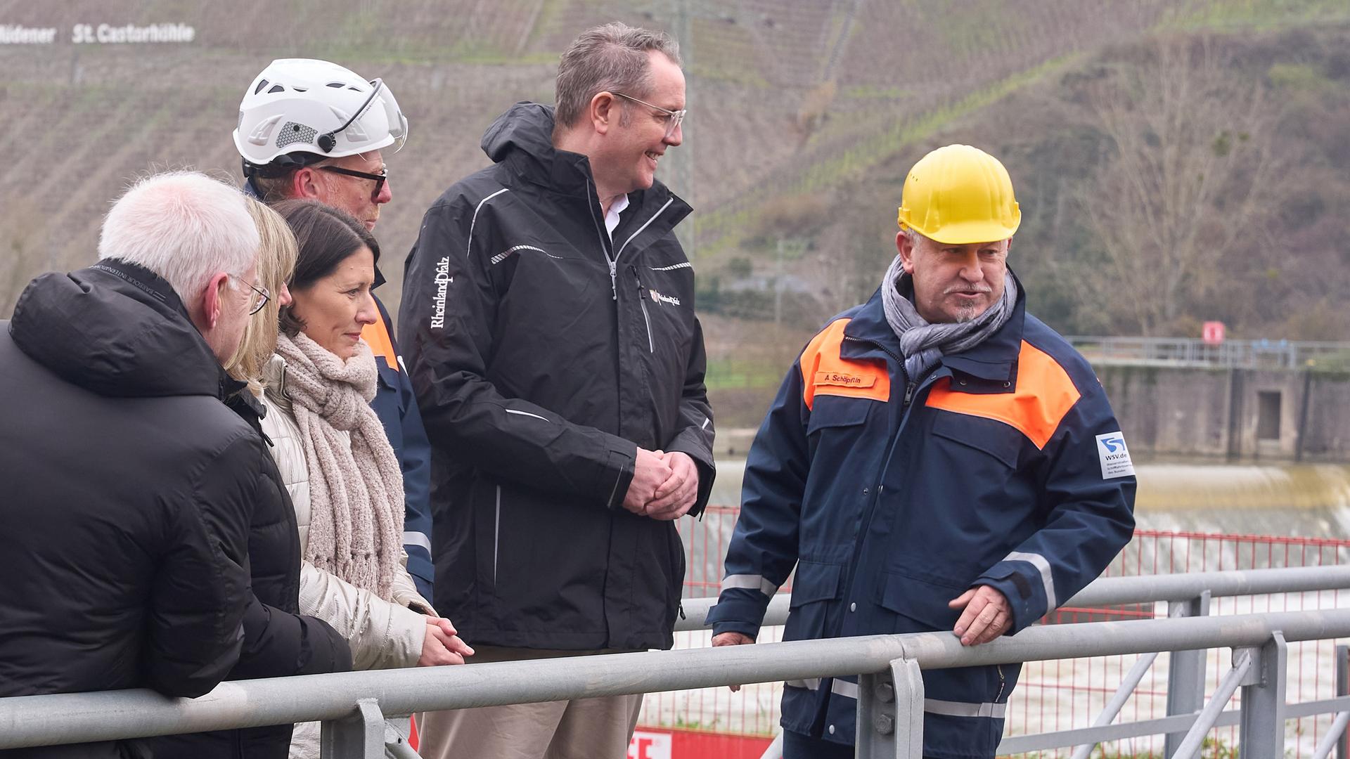 Die rheinland-pfälzische Verkehrsministerin Daniela Schmitt (FDP, l ) und der rheinland-pfälzische Ministerpräsident Alexander Schweitzer (SPD) stehen auf dem Tor der Schleuse Müden, die durch die Kollision mit einem Frachtschiff beschädigt wurde.