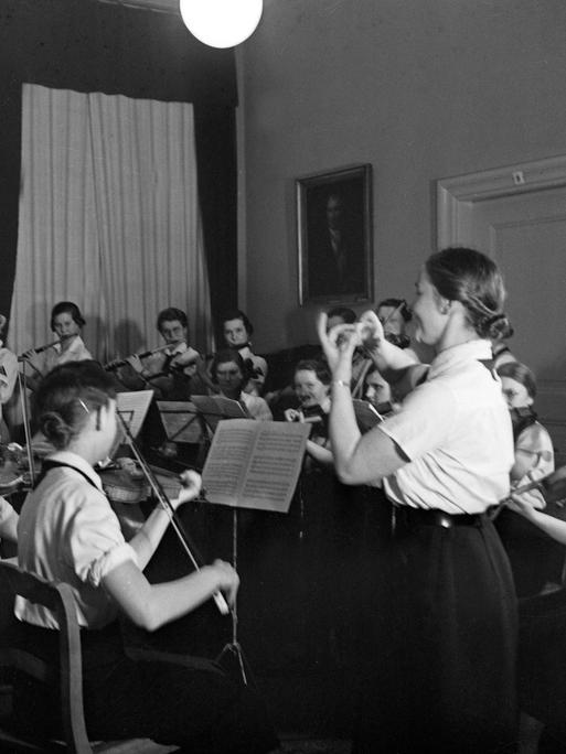 Ein Orchester des "Bund Deutscher Mädel" spielt Geigen und Flöten.