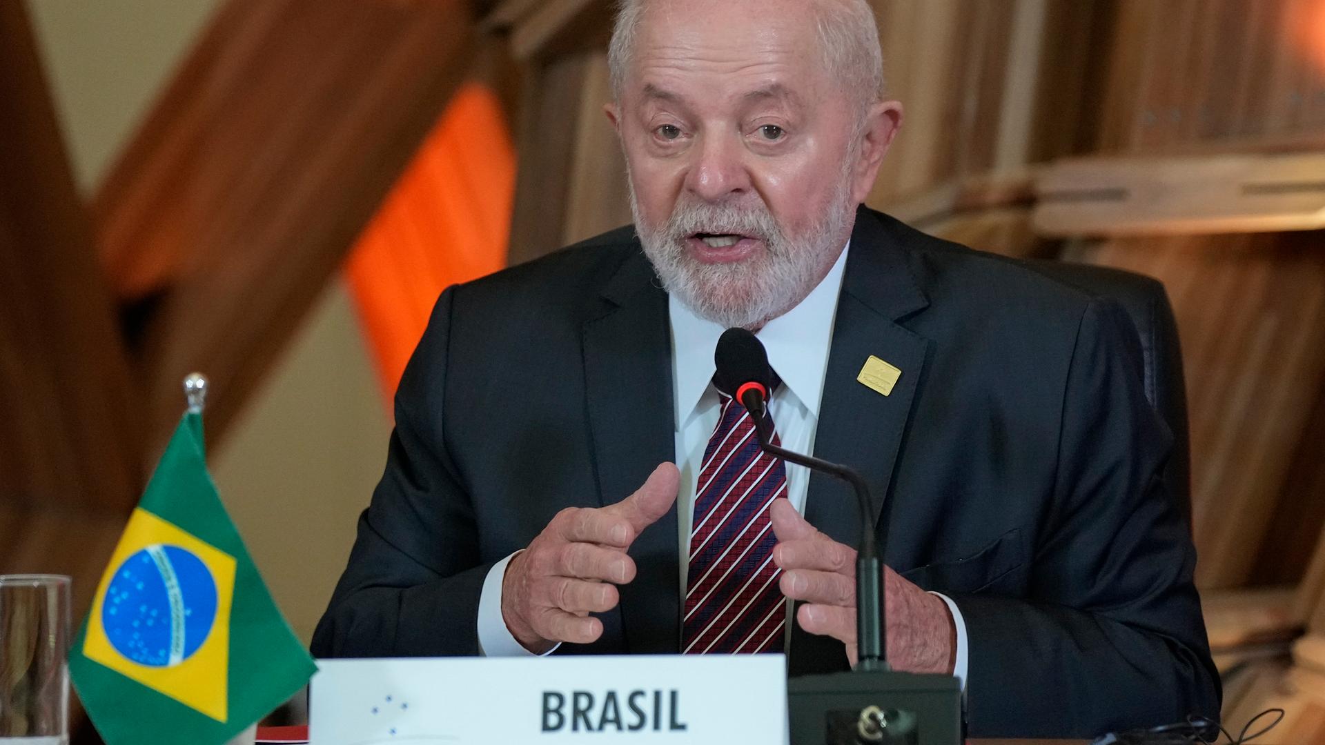 Brasilien Präsident Lula da Silva sitzt an einem Tisch mit einer kleinen brasilianischen Flagge und einem "Brasilien"-Schild