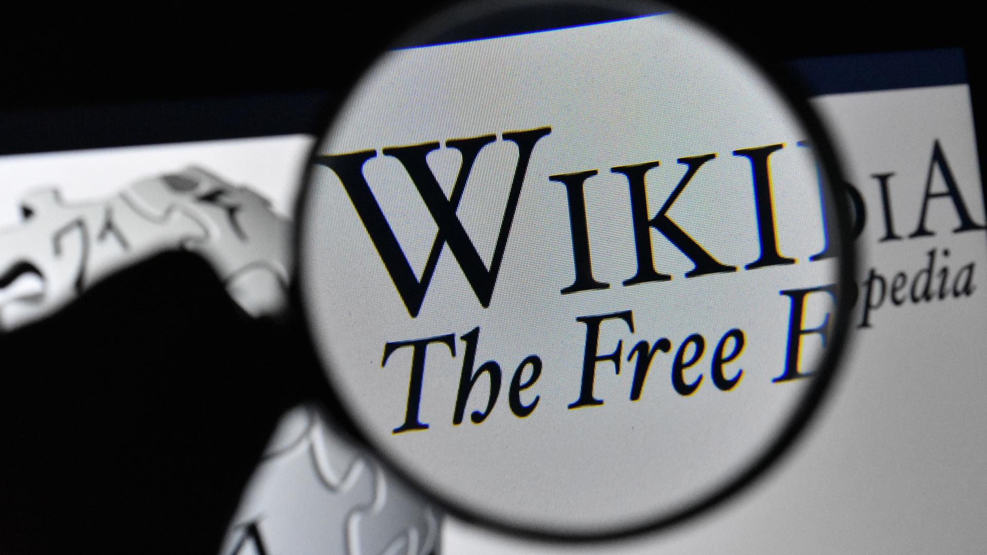 Illustration: Das Logo von Wikipedia durch eine Lupe gesehen, mit dem Wort "Free" auf dem Bildschirm. Illustration: Das Logo von Wikipedia durch eine Lupe gesehen, mit dem Wort "Free" auf dem Bildschirm.