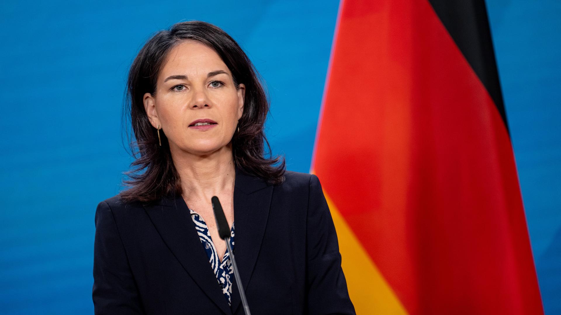 Außenministerin Baerbock gibt ein Statement im Auswärtigen Amt. Sie blickt ernst in die Kamera. Hinter ihr ist eine Deutschland-Flagge.