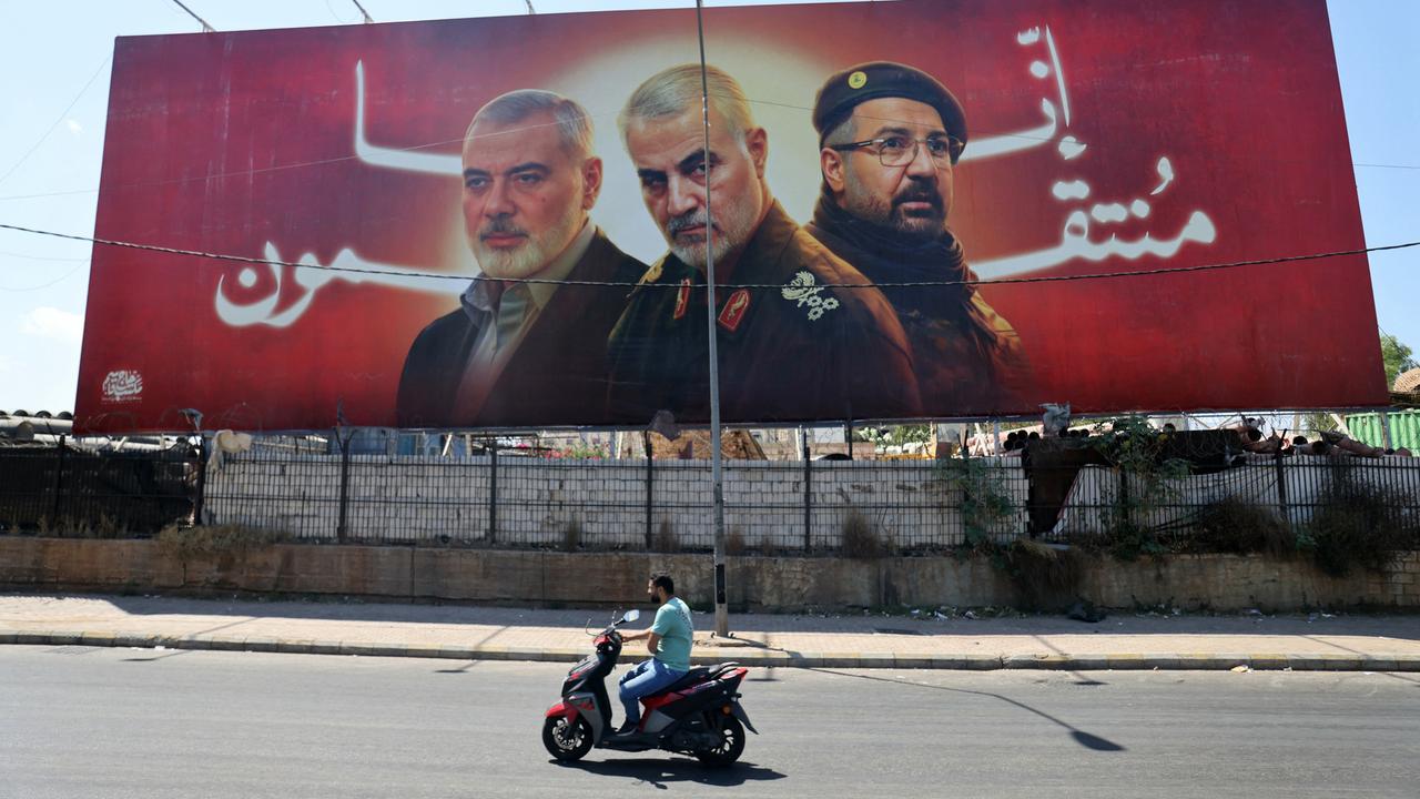 An einer Straße steht ein Banner mit Porträts der getöteten Milizenführer Ismail Haniyeh, Qasem Soleimani und Fuad Shukr.