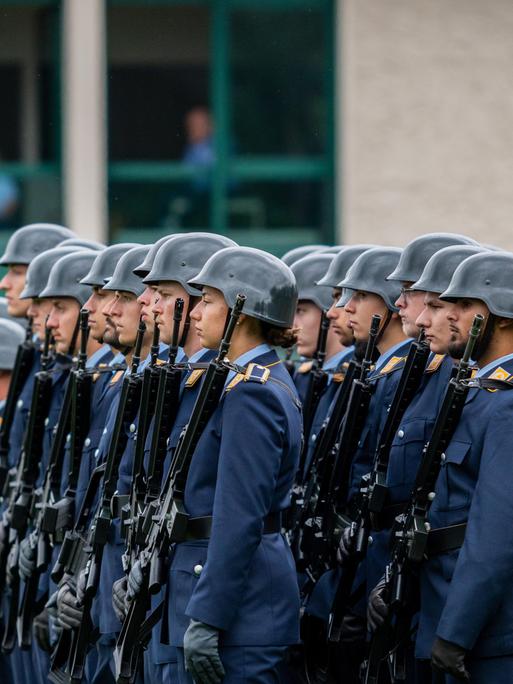 Appell zur Verabschiedung des 124. Offizierslehrgangs der Luftwaffe der Bundeswehr in der Kaserne in Fürstenfeldbruck. Soldaten in blauen Uniformen und Helmen stehen in Formation mit Gewehren. Neben ihnen eine Fahne mit dem Symbol des Bundesadlers.