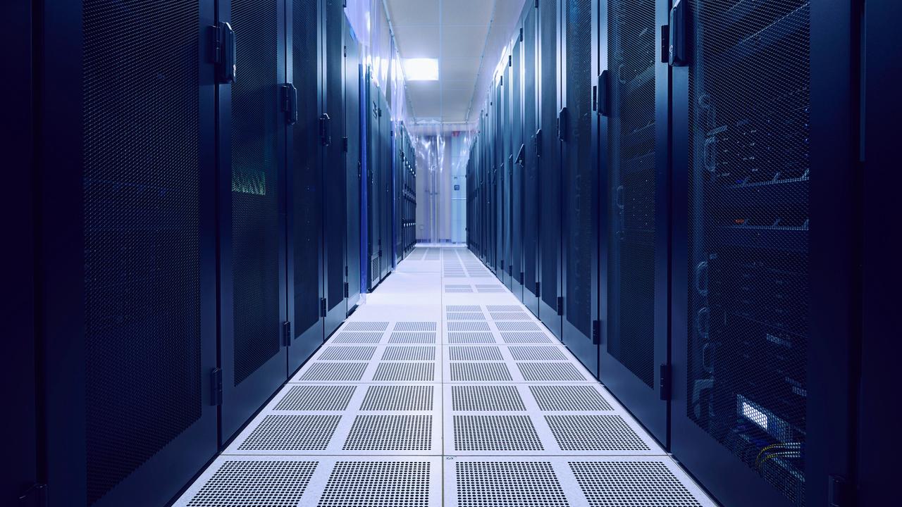 Blick in einen leeren Serverraum. Links und rechts stehen dunkle Serverschränke.