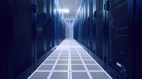 Blick in einen leeren Serverraums. Links und rechts stehen dunkle Serverschränke.