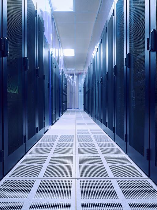 Blick in einen leeren Serverraum. Links und rechts stehen dunkle Serverschränke.