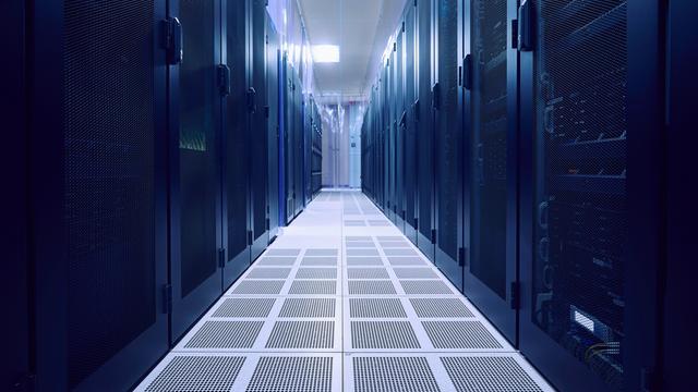 Blick in einen leeren Serverraum. Links und rechts stehen dunkle Serverschränke.