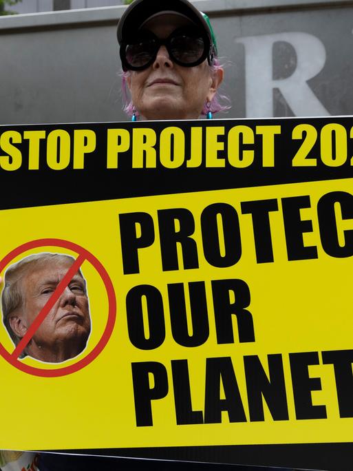 Ein Anti-Trump-Protestler der Aktivistengruppe Rise & Resist hält vor dem Trump International Hotel & Tower ein Schild mit einem durchgestrichenen Bild von Trump mit der Aufschrift "STOP PROJECT 2025 PROTECT OUR PLANET! 