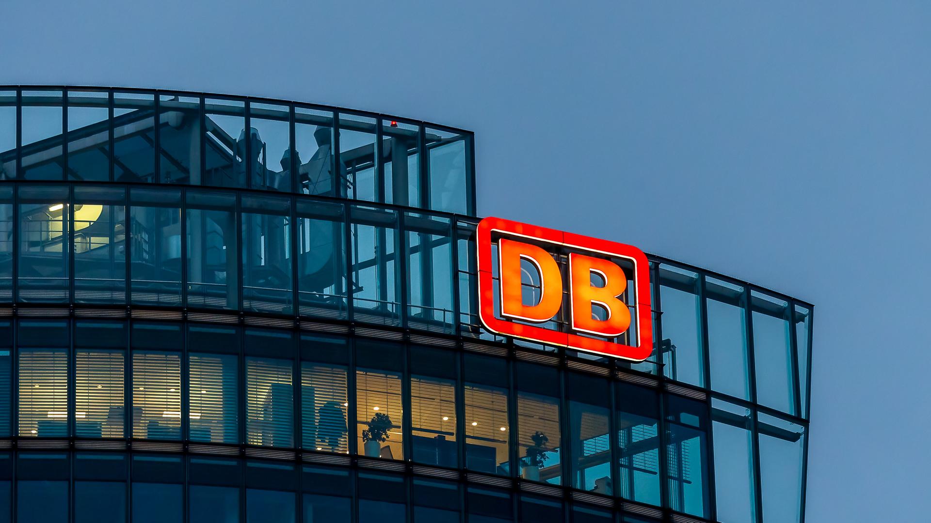 Das Bild zeigt die Vorstandsetage der Zentrale der Deutschen Bahn in der Dämmerung, außen am Gebäude prangt das rote DB-Logo. Das Bild zeigt die Vorstandsetage der Zentrale der Deutschen Bahn in der Dämmerung, außen am Gebäude prangt das rote DB-Logo.