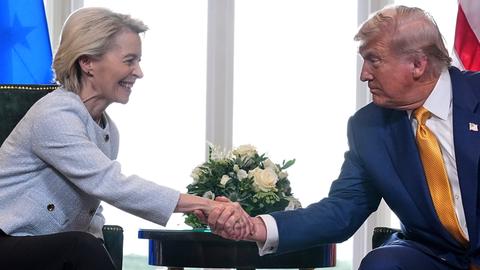 Donald Trump and Ursula von der Leyen schütteln sich sitzend die Hände.
