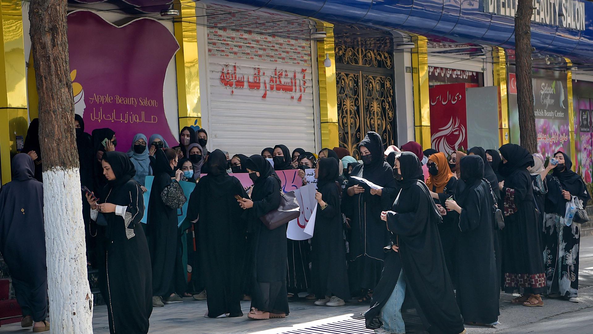 Frauen stehen in Kabul vor einem geschlossenen Schönheitssalon und demonstrieren gegen die Schließung. Frauen stehen in Kabul vor einem geschlossenen Schönheitssalon und demonstrieren gegen die Schließung.