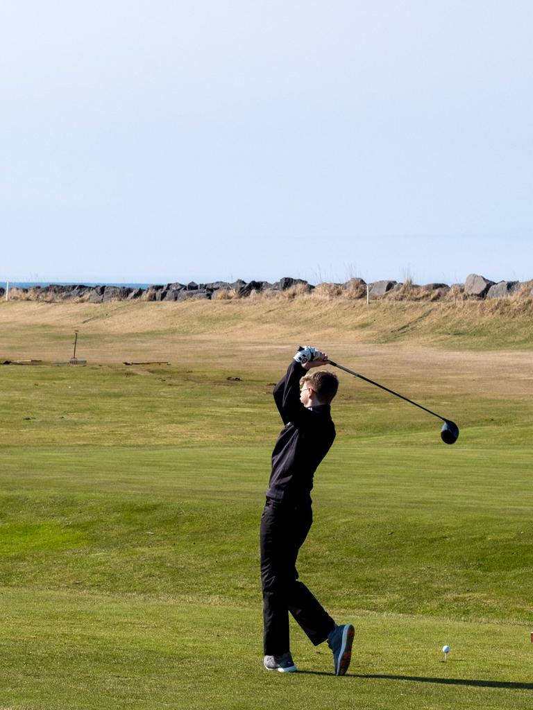Ein Mann steht auf der Wiese und schwingt seinen Golfschläger durch die Luft.
