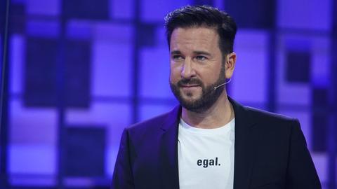 Michael Wendler steht in einem TV-Studio, auf seinem weißen T-Shirt steht "egal"