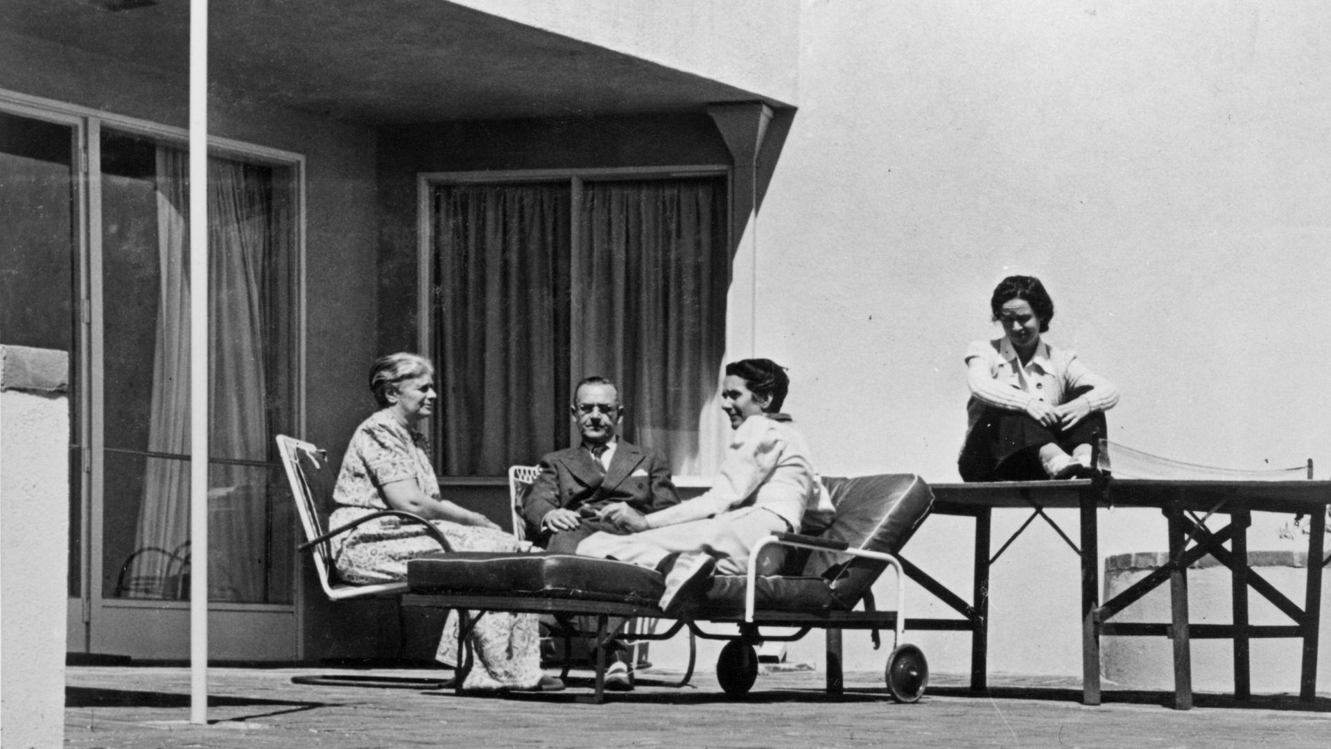 Historisches Schwarzweißfoto: Thomas Mann, seine Ehefrau Katia und die Töchter Erika und Monika sitzen auf der Terrasse seines Hauses in Pacific Palisades.
