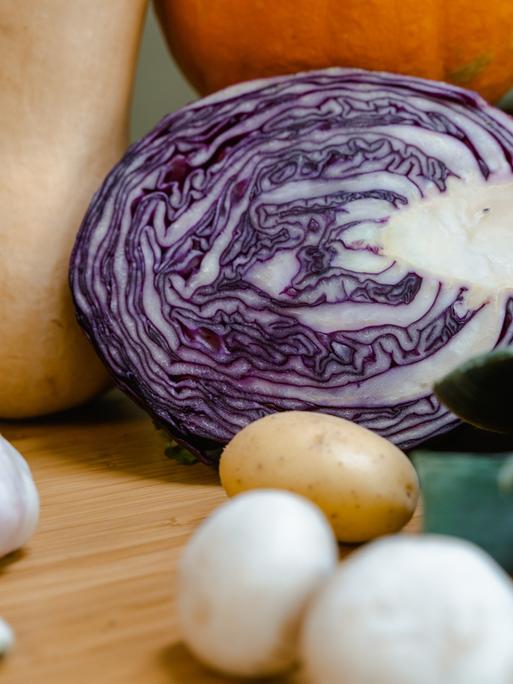 Ein aufgeschnittener Rotkohl liegt zusammen mit anderen Gemüsesorten in einer Küche. 