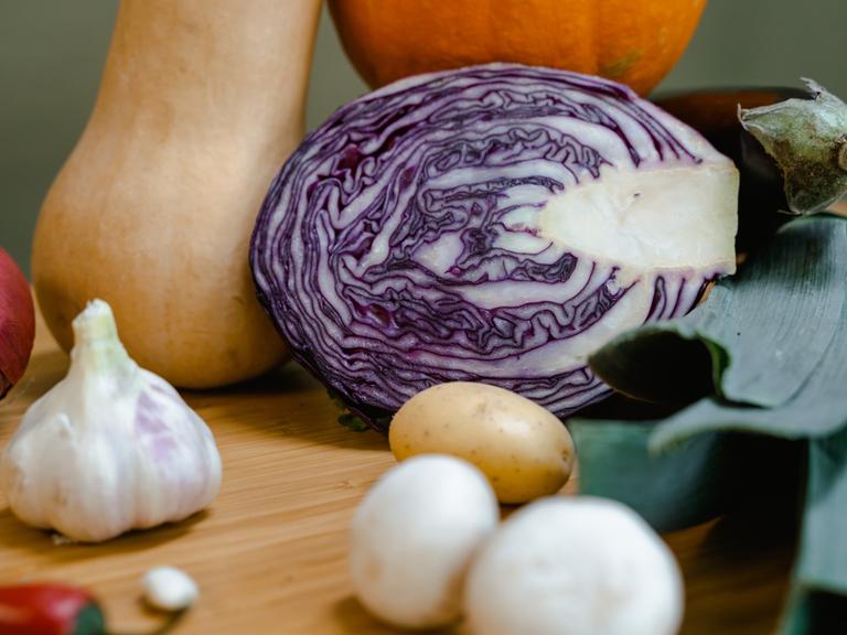 Ein aufgeschnittener Rotkohl liegt zusammen mit anderen Gemüsesorten in einer Küche. 