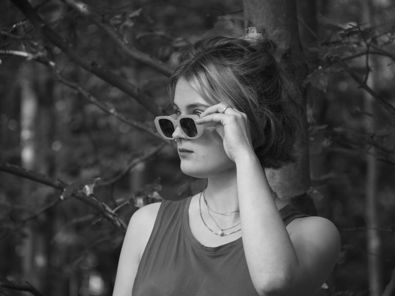 Eine junge Frau hält ihre Sonnenbrille, während sie über den Rand in die Ferne schaut