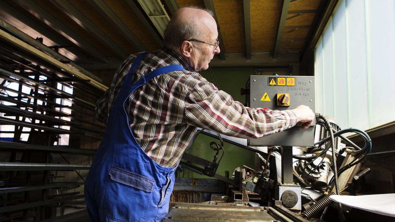 Ein älterer Herr arbeitet in einem mittelständischen Unternehmen für Maschinenbauteile.