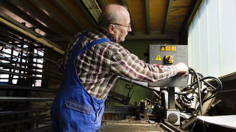 Ein älterer Herr arbeitet in einem mittelständischen Unternehmen für Maschinenbauteile.
