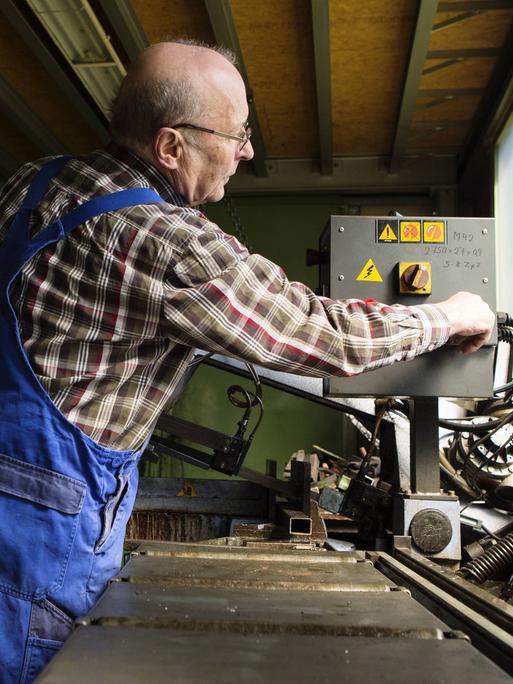 Ein älterer Herr arbeitet in einem mittelständischen Unternehmen für Maschinenbauteile.