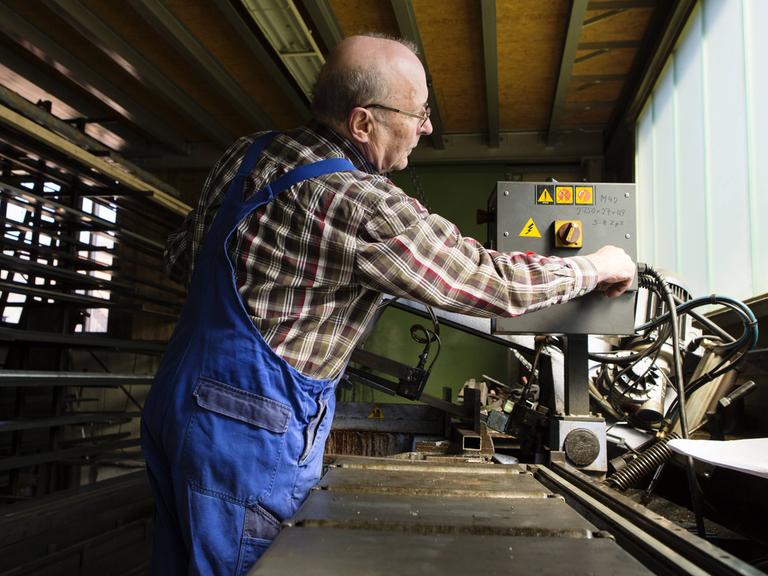 Ein älterer Herr arbeitet in einem mittelständischen Unternehmen für Maschinenbauteile.