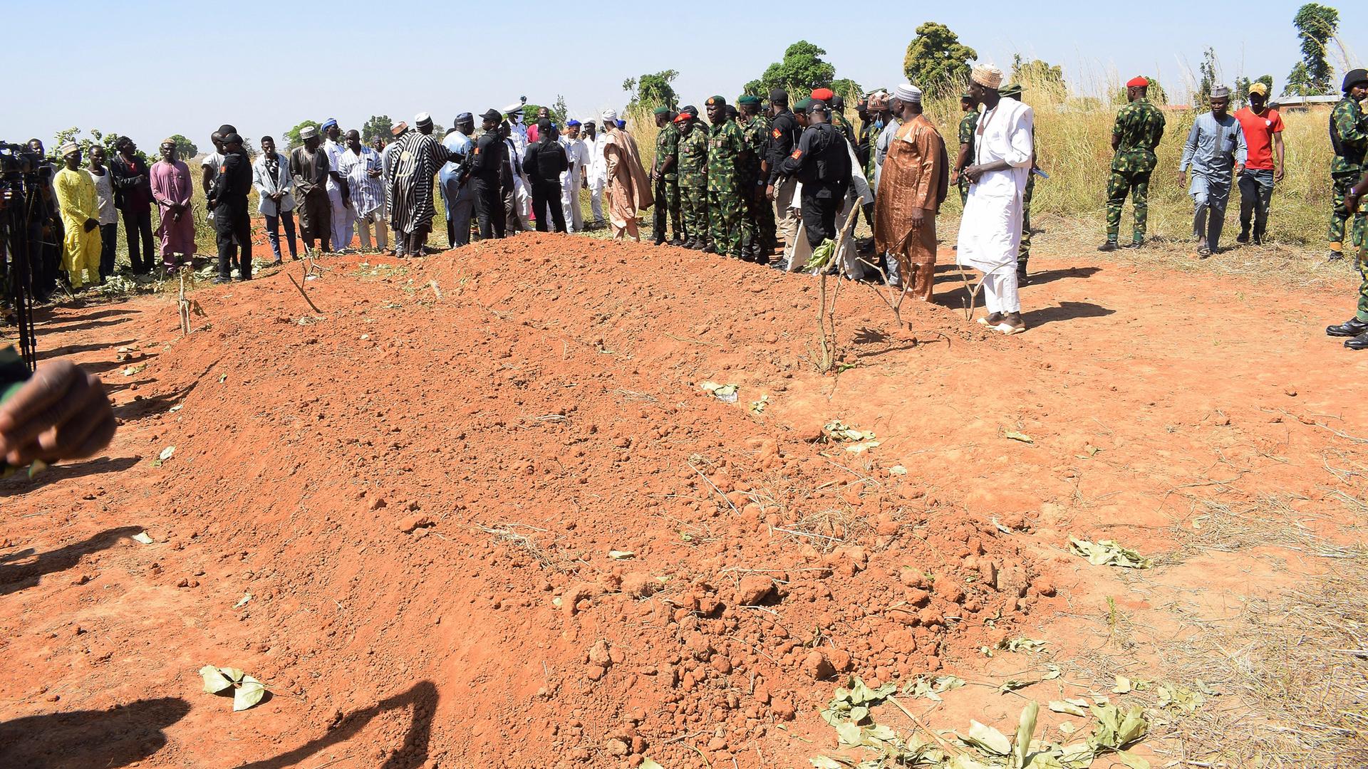 Menschen stehen um einen Hügel in Nigeria herum, in dem die Opfer des Drohnenangriffs begraben wurden.