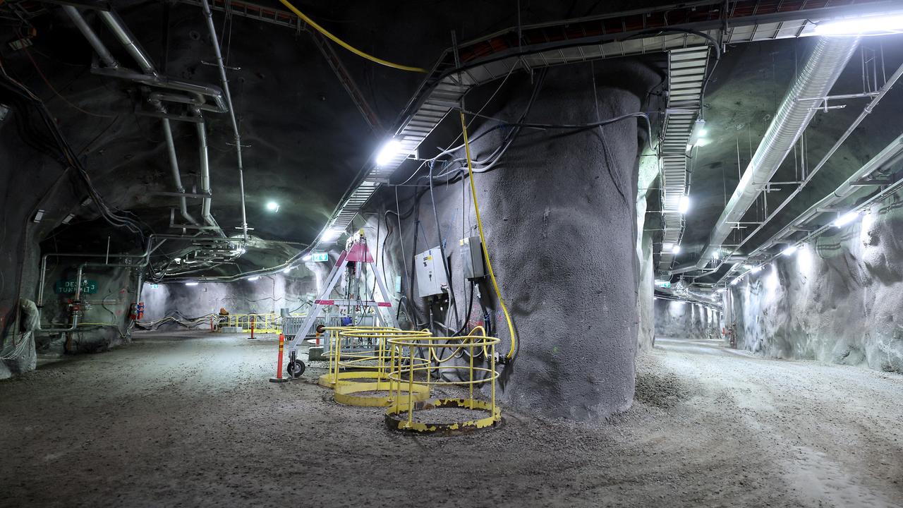 Eine unterirdische Anlage. Sie ist hell erleuchtet. Man sieht ein eine Weggabelung. Unter der Decke sind viele Kabel. 