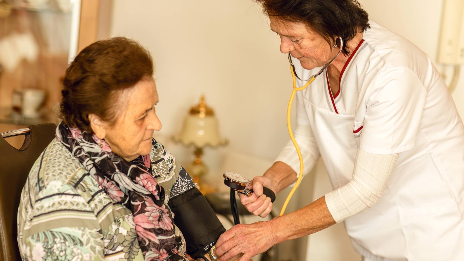 Eine häusliche Krankenschwester misst den Blutdruck einer älteren Frau im Rahmen der Herz-Kreislauf-Überwachung. Eine häusliche Krankenschwester misst den Blutdruck einer älteren Frau im Rahmen der Herz-Kreislauf-Überwachung.