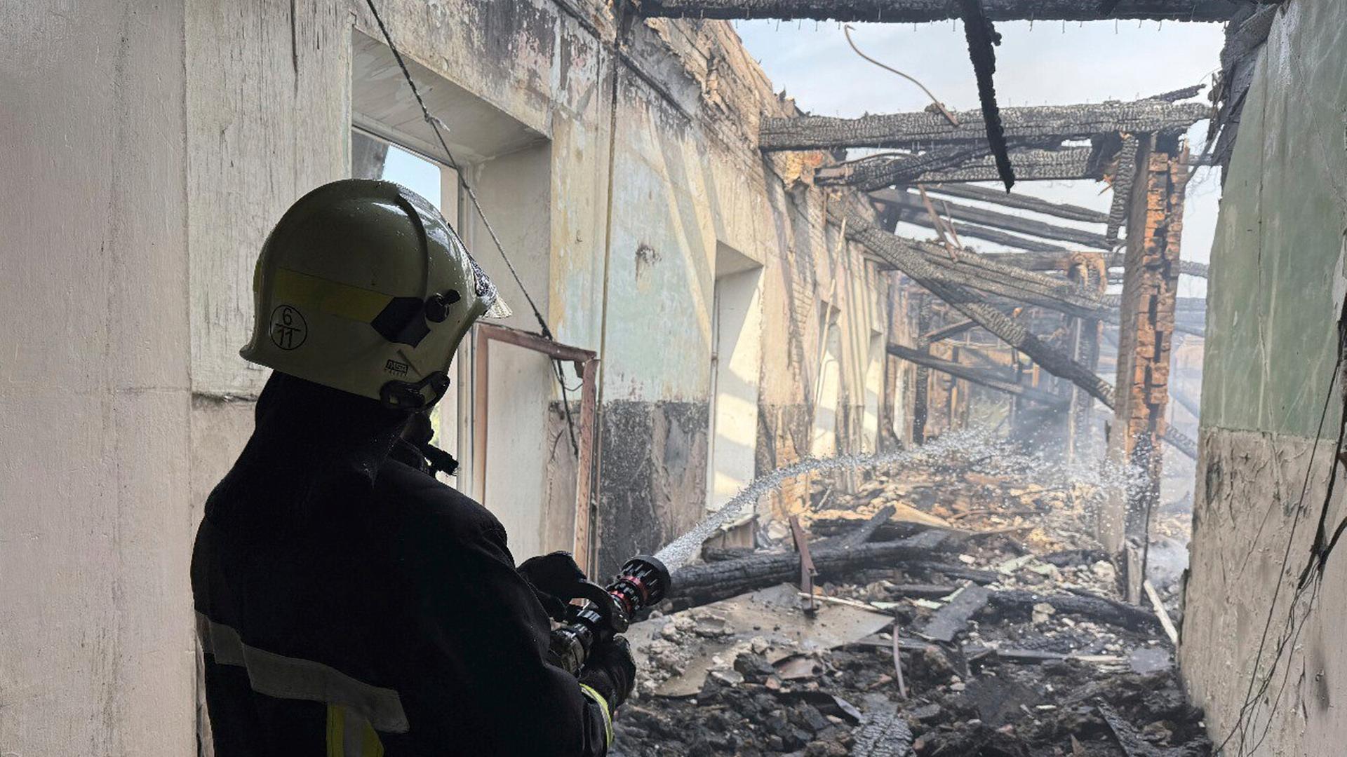 Ein Feuerwehrmann löscht ein Feuer an einem Haus in der Ukraine nach einem russischen Drohnenangriff. 