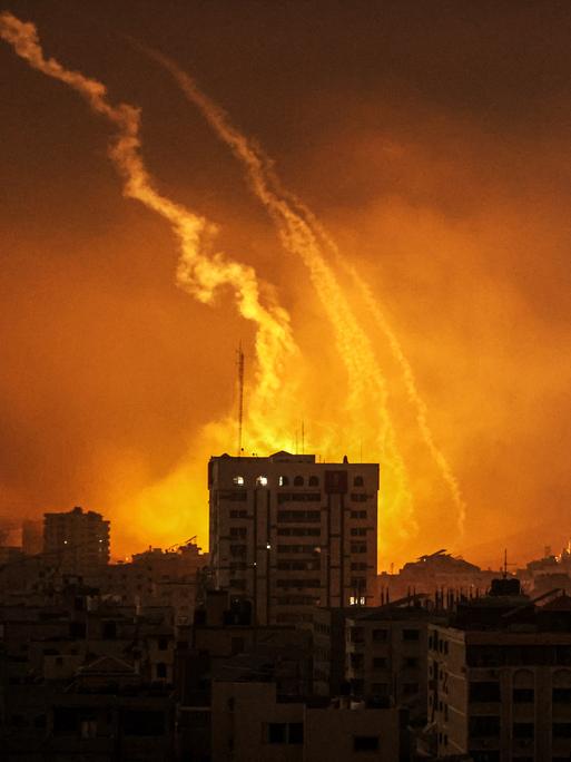 Rauch steigt aus Gaza vor einem von Feuer erleuchteten Nachthimmel auf, nachdem Israels Armee weitere Luftangriffe gegen die Hamas-Terroristen geflogen hat. 
